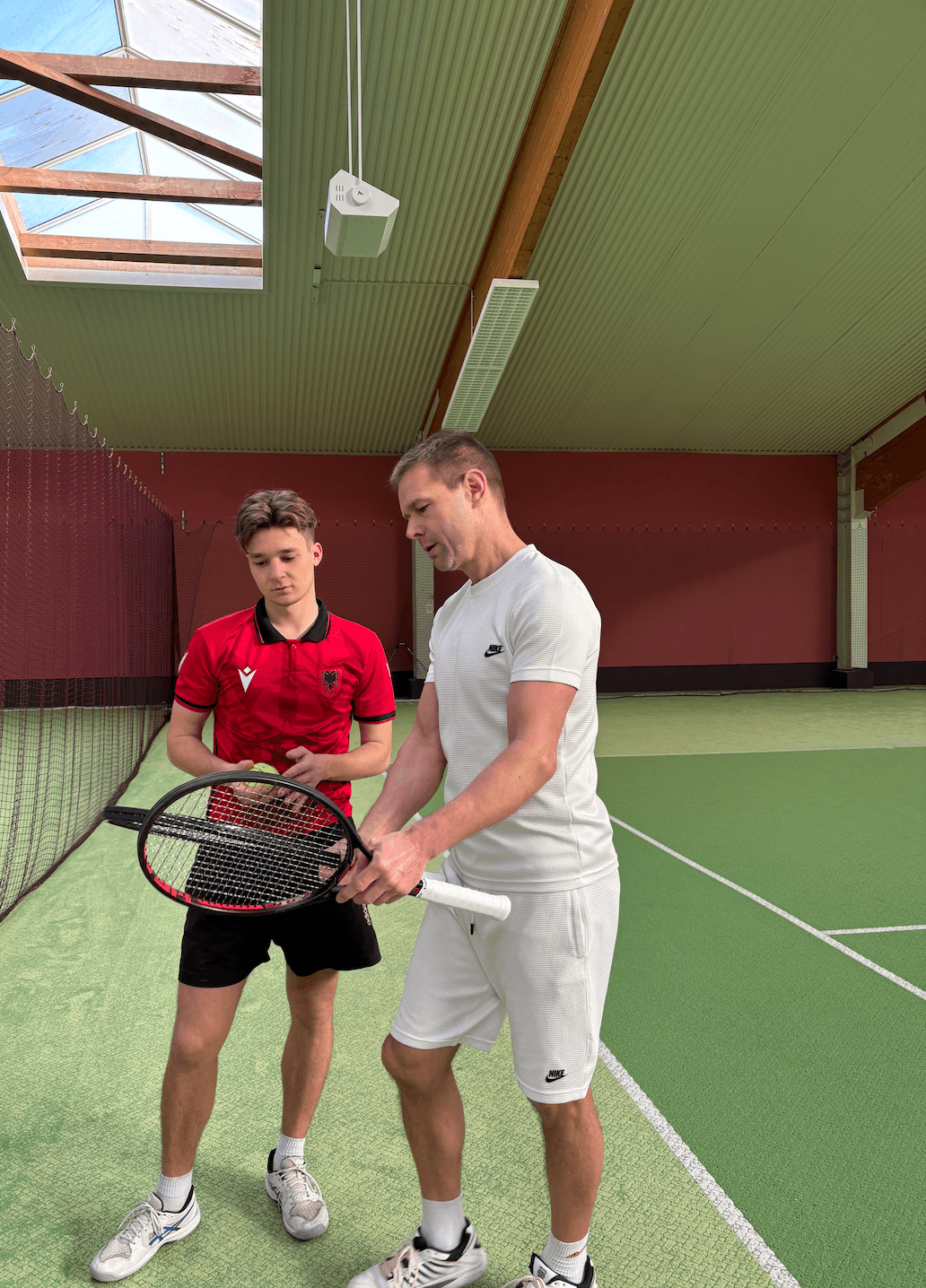 Tennistrainer erklärt seinem Schüler etwas